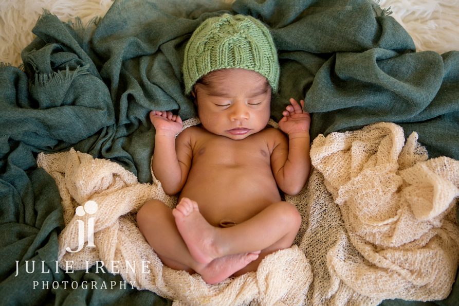 green tones newborn baby boy curled up in blanket