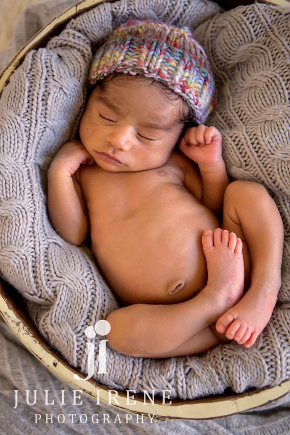 Baby boy newborn curled in bucket