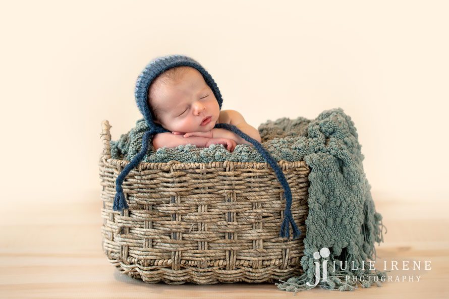 blues newborn in a basket with blue knit hat