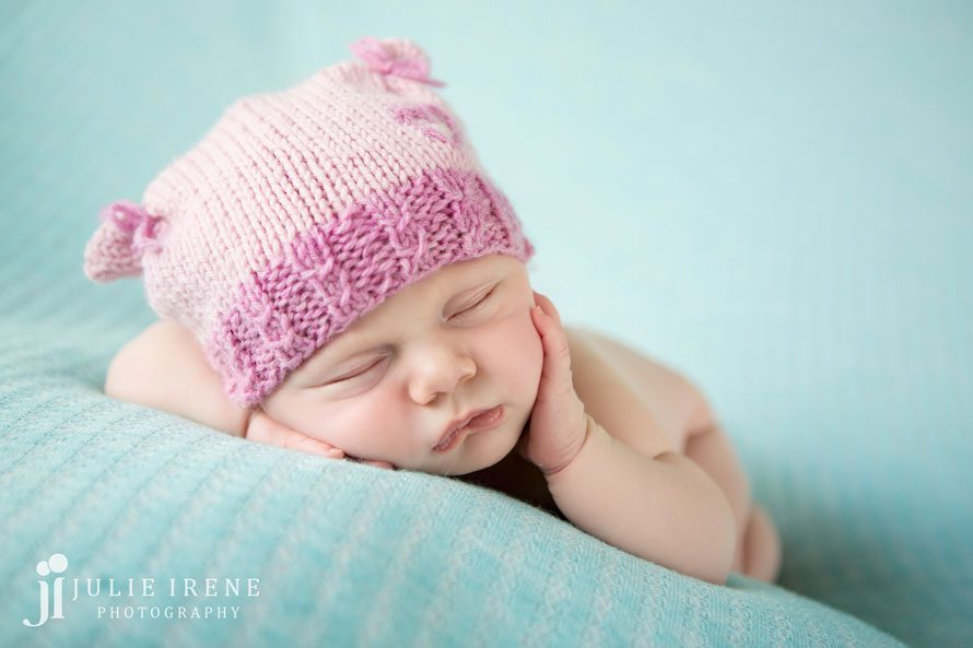 newborn baby girl pink hat hand cheek