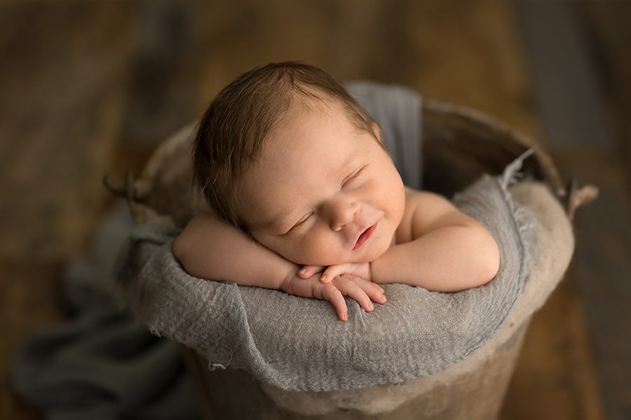 cute newborn smirk posed in a bucket