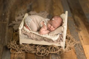 mia joy outfit on a newborn girl with cream bed on barn wood floor