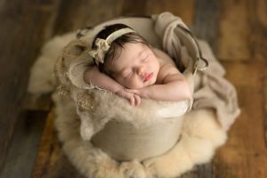 gorgeous newborn girl in cream bucket and rabbit fur