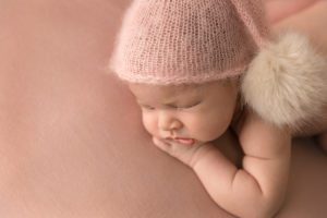 newborn wearing a pom pom hat