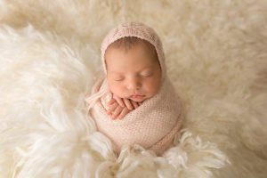 pink knit wrap and bonnet on cream flokati
