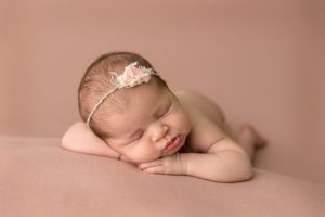 newborn girl on pink rug with adorable lips
