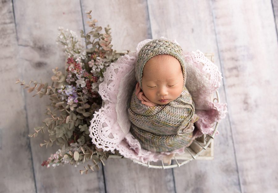 newborn girl with lavender flowers in white crate