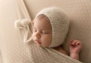 sleeping newborn girl with knit pom pom bonnet