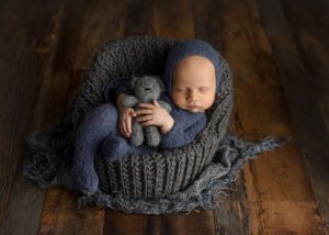 moody newborn image of boy with teddy bear sitting in a chair
