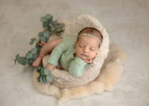 cute baby girl sitting in a posing pod with greenery