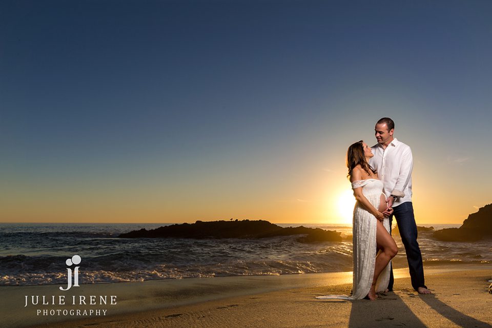 pregnant mom and husband in ocean with california sunset