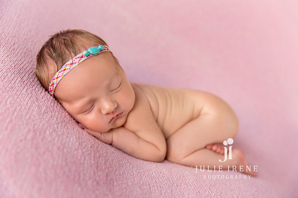 newborn girl in tribal headband on pink in San Clemente