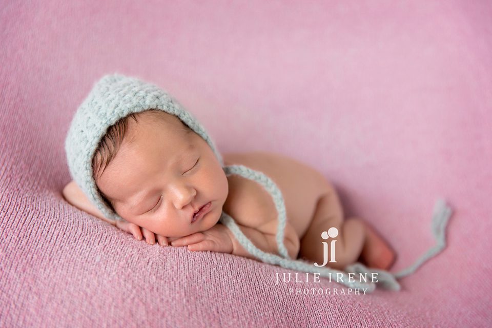 newborn girl in orange county with teal bonnet on pink