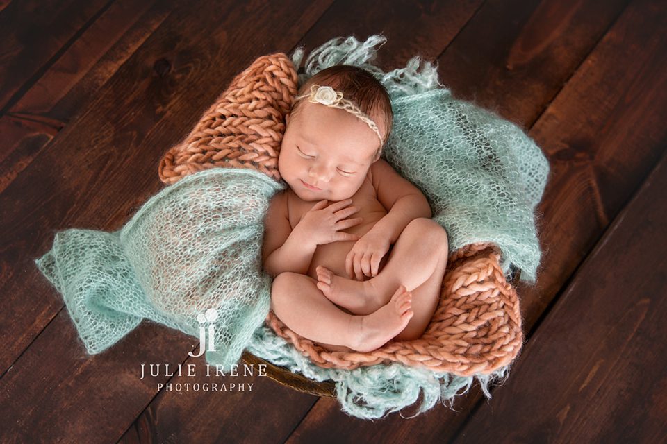 newborn girl on back in teal and coral oc