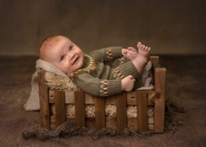 happy baby in a little wood bed