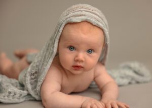 four month old boy with scarf over head