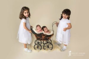 newborn twins in baby carriage with twins