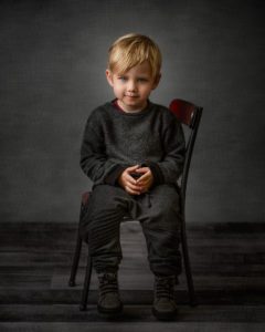 cute toddler looking ornery sitting in a metal chair