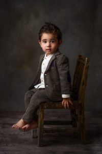 a boy sitting in a chair getting his portrait taken
