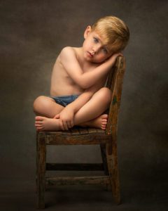 3 year old boy sitting in an antique chair