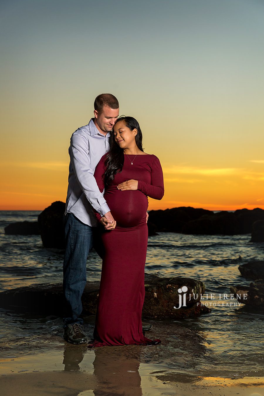 romantic shot of pregnant mom and husband at the beach