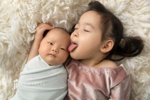 sister licking brother in newborn portraits