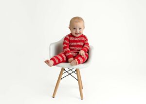 baby in red knit outfit sitting in chair