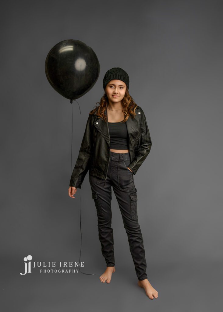 Teen girl holding a black balloon in a photos shoot